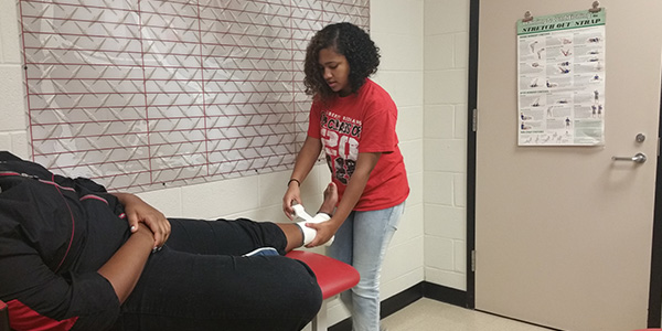 Taping an ankle is just one of the many tasks sophomore Sabrina Poole and other student trainers perform on a daily basis. 