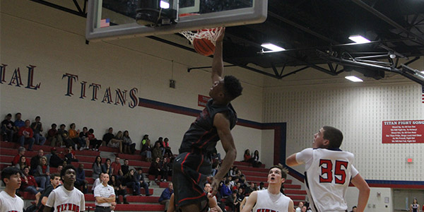 Surrounded by Centennial players, sophomore Reggie Chaney gets two of his 14 points on this one handed dunk Saturday, Jan 2, 2016 at Centennial in the 60-39 win over the Titans.