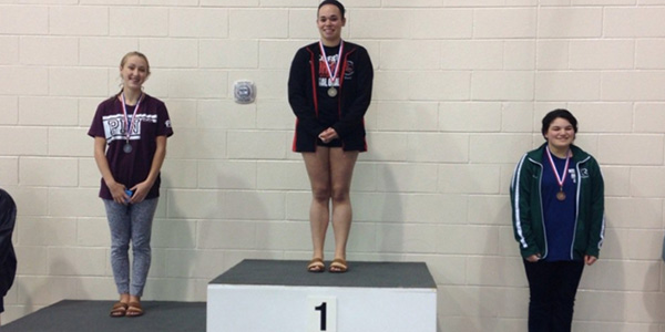 Setting a slew of records, senior Lauren Burrell stands atop the podium after winning the district diving championship. 