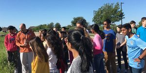 Students gather around AP Human Geography teacher in the corn field next to campus to discuss their unit on agriculture. 