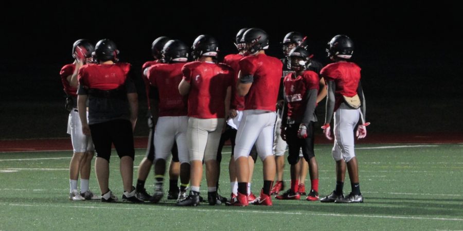 Varsity players in team huddle during live scrimmage as part of Redhawk Rally. The team opens it season with a district game. 