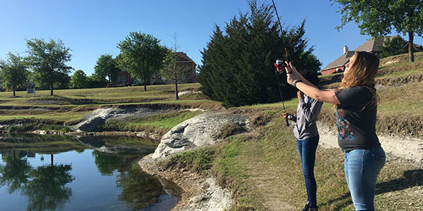 Holding her fishing rod in the air, sophomore Laurel Sell stands along the bank of the pond at Turnbridge Limestone Park.