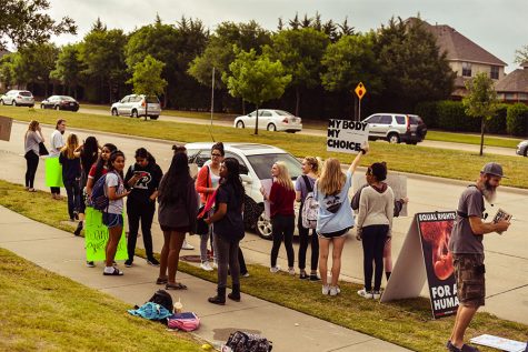 With a line of cars waiting to turn into the schools main entrance, students protest in front of the school on the morning of Thursday, May 18, 2017. 