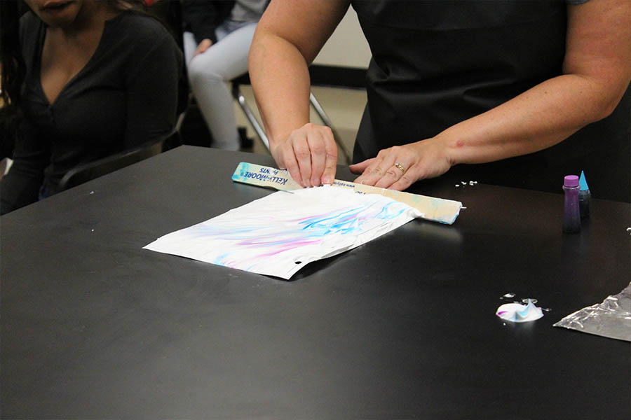 Placing shaving cream and food coloring on the back of the syllabus, science teacher Lara Russey demonstrates marbleizing on the first day of school Monday, Aug. 21, 2017. 

marbleizing