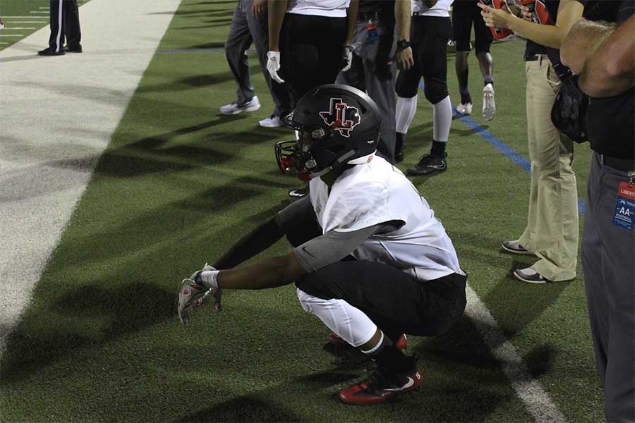 Senior Javon Greene stretches from the sideline as he watches the Wolverines take the win 51-17.