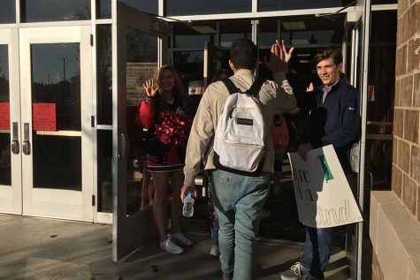 Pulse vice president Wade Glover and cheerleader Peyton Leonard welcome senior Noah Servigon with a high five on the second High Five Friday. 