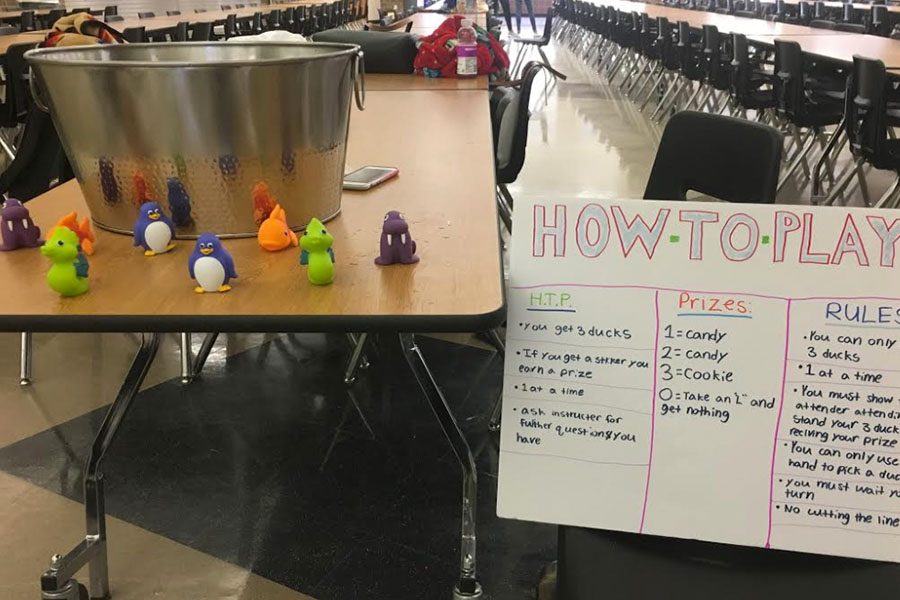 Carnival games are set up in the cafeteria, and students take notes on the players score.