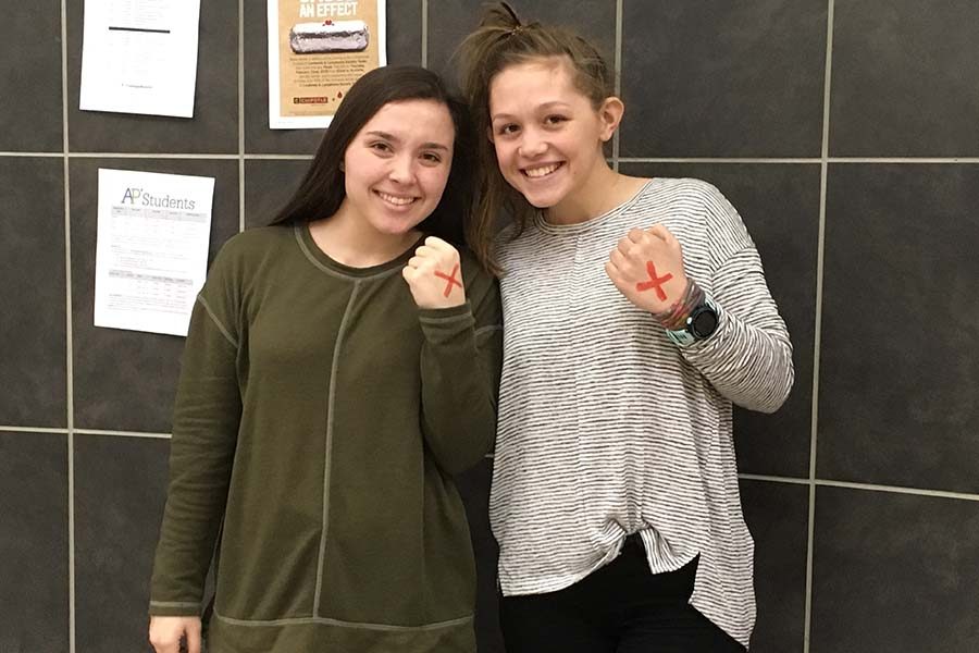 With a red x on each of their left hands, juniors Mara Casey and Madeline Kennedy are taking part of in “Shine A Light On Slavery Day” to bring awareness  to modern day slavery. 