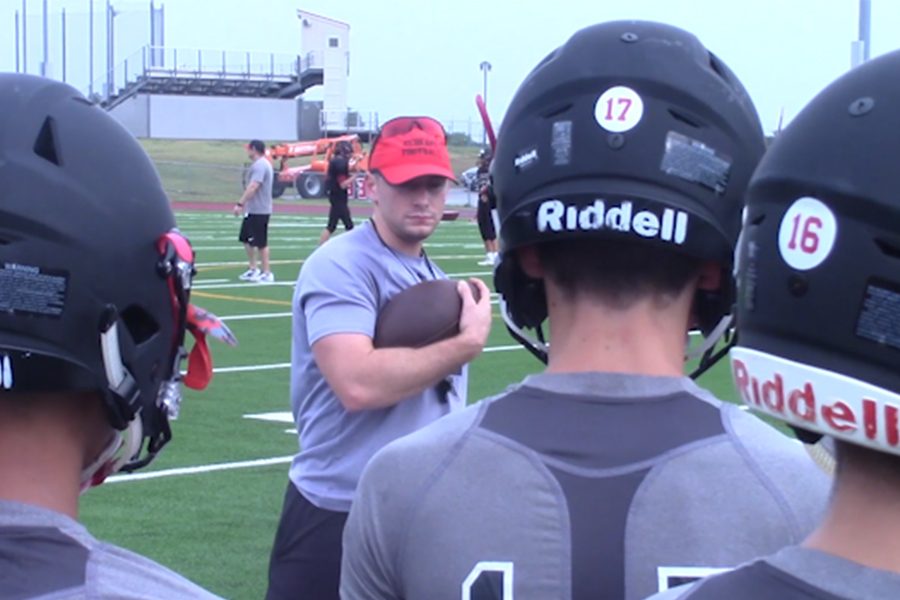 Assistant football coach Kenny Schiumo demonstrates how to hold the ball. It's a tip that could be especially helpful Friday night as the team takes on Carrollton Creekview in what could be wet game with rain in the homecoming forecast. 