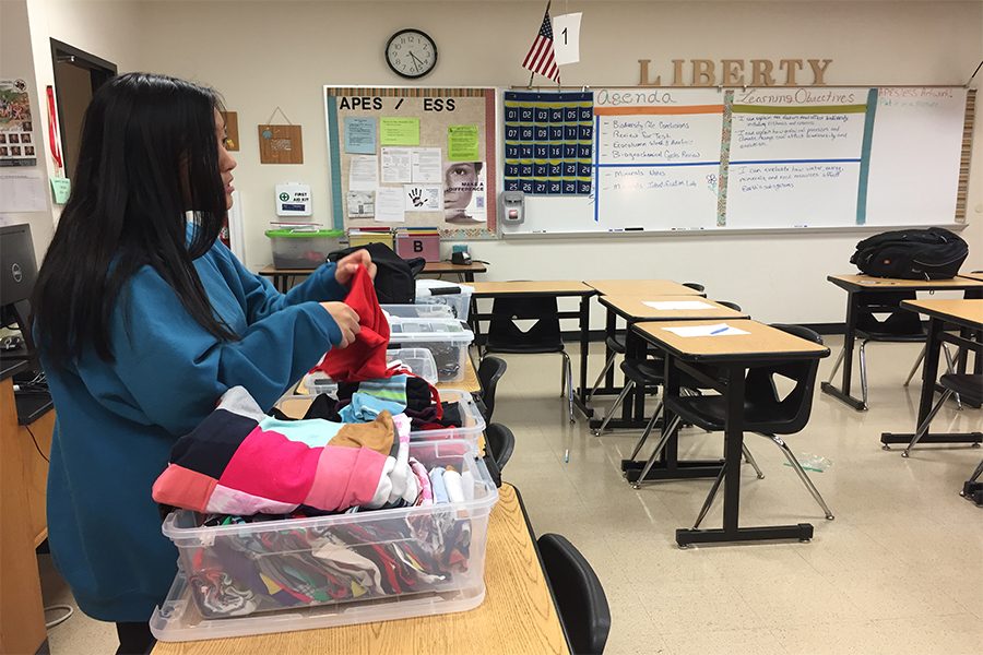 One Thread Club leader, Ayda sow, folds and organizes the various fabrics the supplies bins for later use. By being neat, it makes it easier for the other club members find their desired fabric among all of the supplies.
