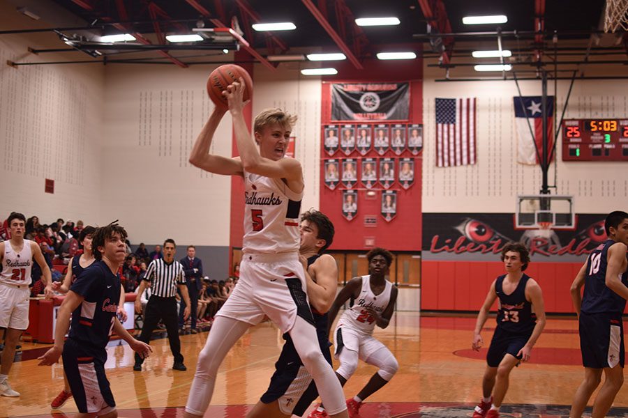 Senior Peyton Harwell (#5) defends the ball from Centennial Titan defender during their showdown on Tuesday, Dec. 18. The Titans and Redhawks will battle it out again Tuesday night at Centennial. 