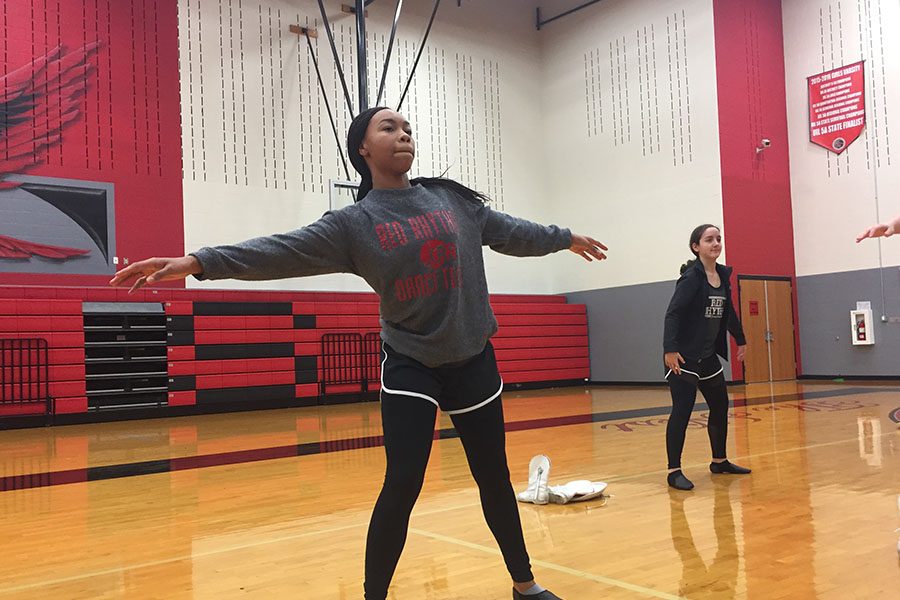 Stretching before practice, freshman Melia Terry participates in both Red Rhythm and orchestra. Having to switch off between the two, Terry will have a packed schedule performing for both in the Winter Extravaganza.