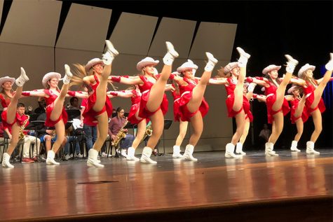 Kicking their legs high in the air, the Red Rhythm dance team practices their Winter Extravaganza performance in the auditorium. Beginning Thursday, the team will resume tryouts for next year. 
