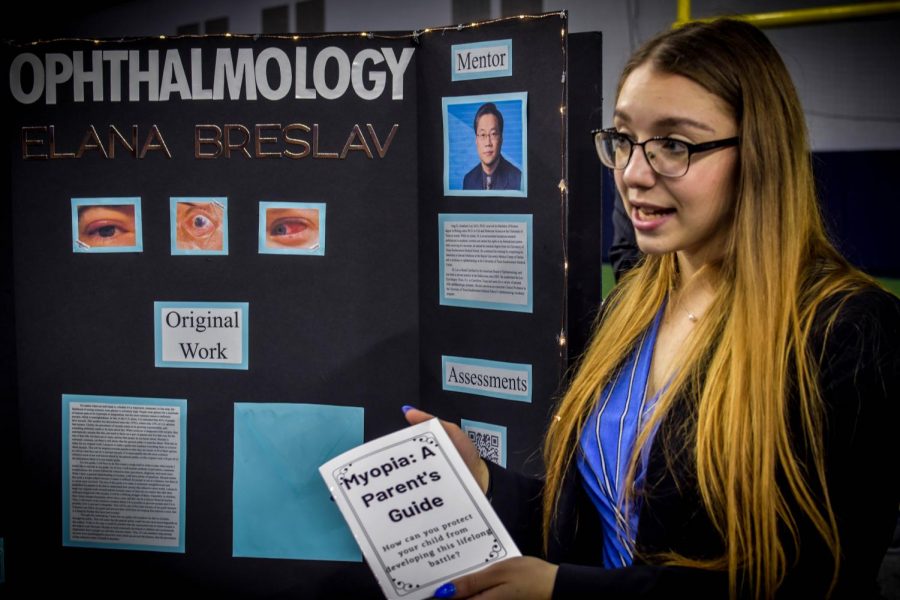 With an opthalmologist as her mentor, senior Elana Breslav presents her research and holds a pamphlet featured in her original work.