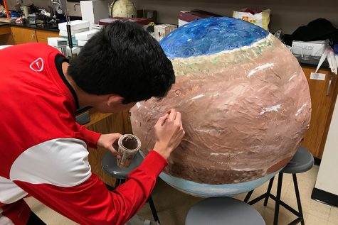 Astronomy students are working on a scale model of the solar system. The students aim to create a model that stretches from the stairs to the gym.