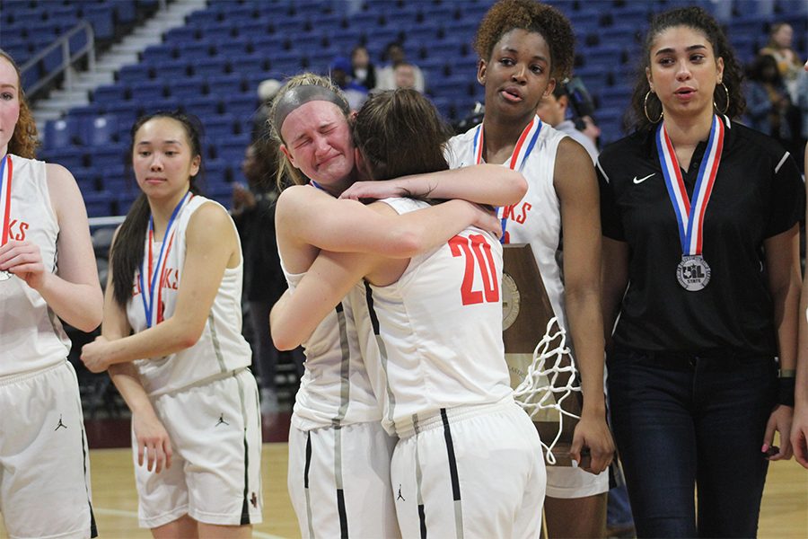 Senior Mackenzie Glover hugs senior Mara Casey following the medal ceremony upon the conclusion of the UIL 5A girls state championship game. Making their second appearance in four years in the state final, the Redhawks lost to the Amarillo Sandies 47-42 in the 5A state championship. 