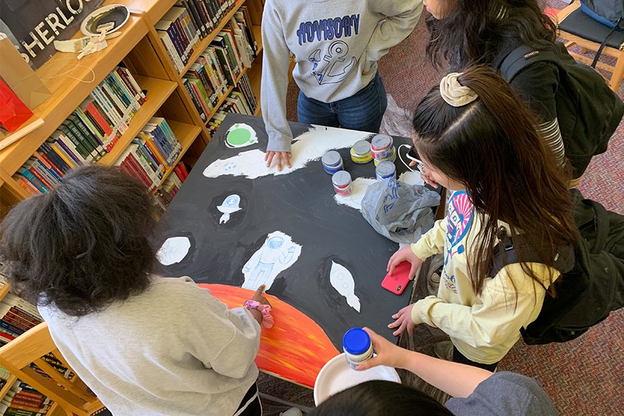 Juniors Fallon Buckner, April Xu, Archana Nagarathinam, Nandasri Talluri and sophomore Anica Liu stand around a table as they plan out ideas and gather needed supplies to begin painting the library tables.