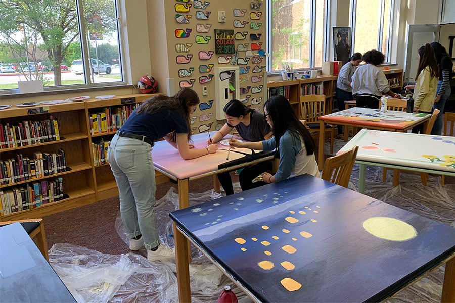 Chosen art students take time out of their art class to paint various library tables in Liberty’s school library. Each group of students paints a table based off of their own design choice.   