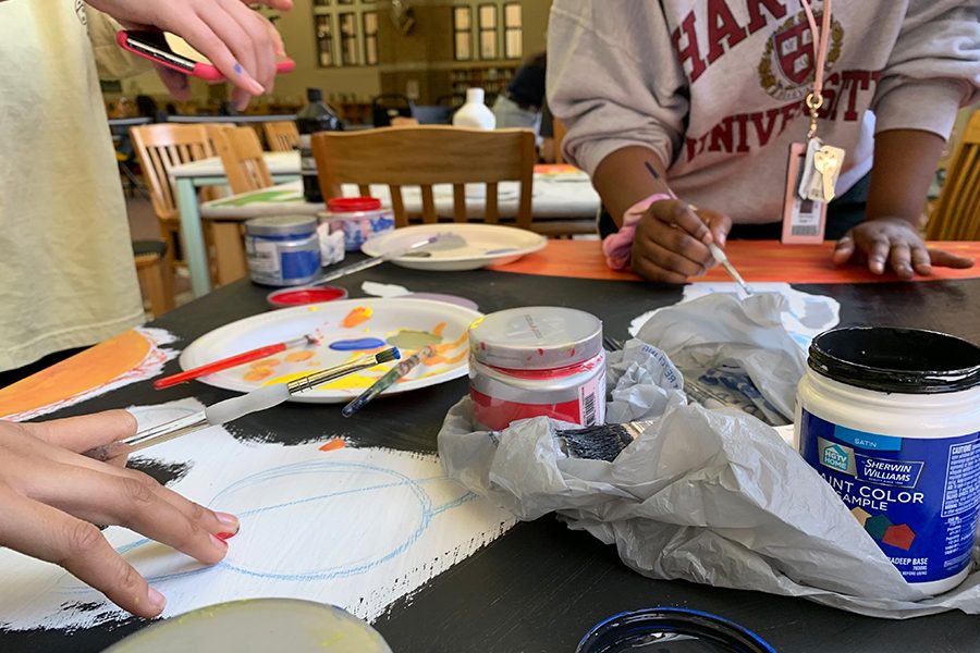 While painting her designated library table, junior April Xu plays music on her phone for her other group members, juniors Fallon Buckner and Archana Nagarathinam, to listen too.  