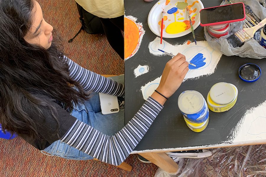 Junior Archana Nagarathinam is in the process of painting a blue planet onto one of the school library tables. 