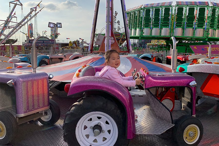 Fair attendee, Leah, smiles to her mother as she rides on a tractor themed fair ride. The Frisco Fair is a entertaining place with rides open for all ages.
