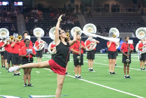 Junior Kimberly Nguyen waves her rifle prop around as a member of Color Guard during a football game at The Star. With marching band season coming to an end, color guard will compete int he UIL Area competition on Saturday in Little Elm. 