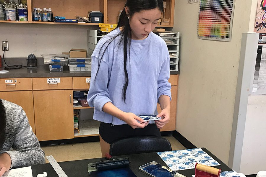 Senior Lauren Tanghongs prepares to stamp her acrylic-covered linoleum block. After stamping, students paint thin layers of acrylic paint onto the gesso-board. 