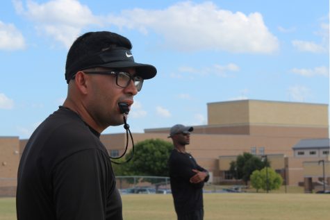 Pictured: football coaching staff stands on the field during summer practice. Football, track athletes, as well as Red Rhythm and Cheer began practices over the summer to prepare for the upcoming school year. 