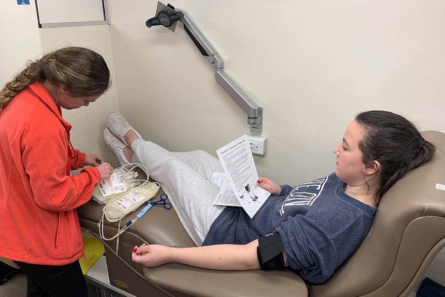 Buses line the school curb near the gym for the semi annual blood drive. Inside, sophomore Mary Hawkins reads an instruction page in the Carter Blood Care bus on Tuesday, Dec. 10, 2019 before donating her blood.