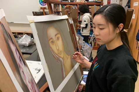 Former senior Lauren Tanghongs paints herself for the portraits project in AP Drawing. Other than using pastels for a change, students learned how to incorporate the skill of realism in their pieces.