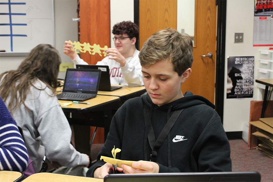 Using scissors to cut out a paper doll chain, freshman Blake Enloe works on his women in agriculture cutout in the AP Human Geography class of Tim Johannes.

Once students finished their cutout, they used Chromebooks to research information and write statistics and facts on their paper doll chain. 
