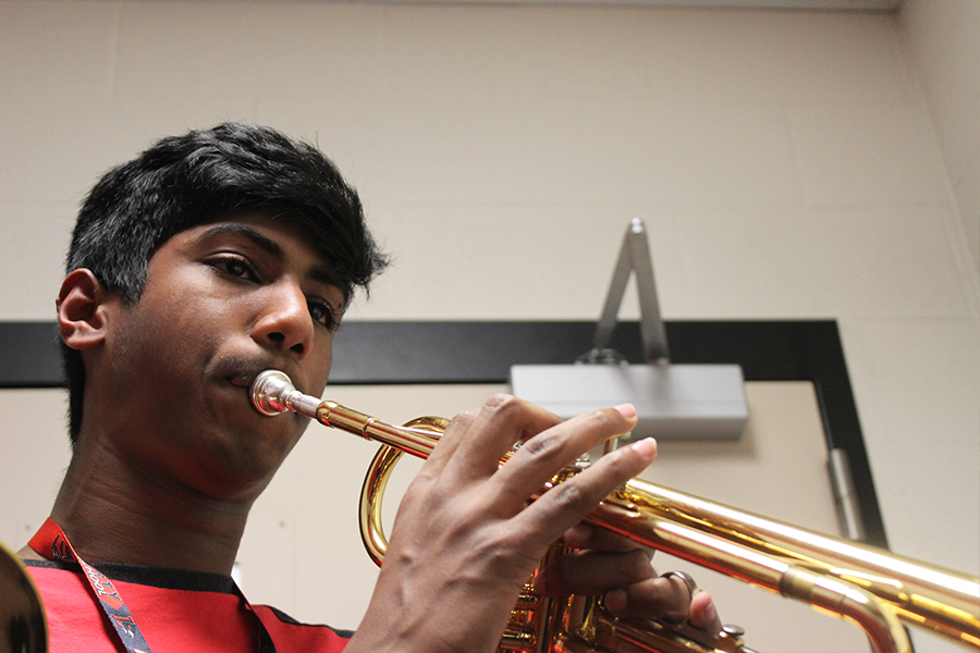 Freshman Adrian George plays trumpet in a practice room. 