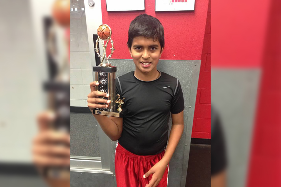 Holding a trophy from his early years in basketball, Philips smiles celebrating his teams success. 