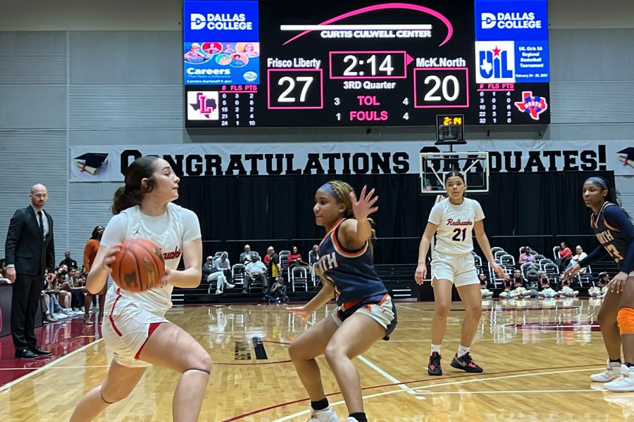 Leading 27-20, Redhawks senior Jezelle Jolie Moreno looks to pass as freshman (#21) Lilian Johnson and head coach Ross Reedy look on. Moreno was convert a 3-point play late in the game to help the Redhawks pull away for a 57-47 win over McKinney North. 