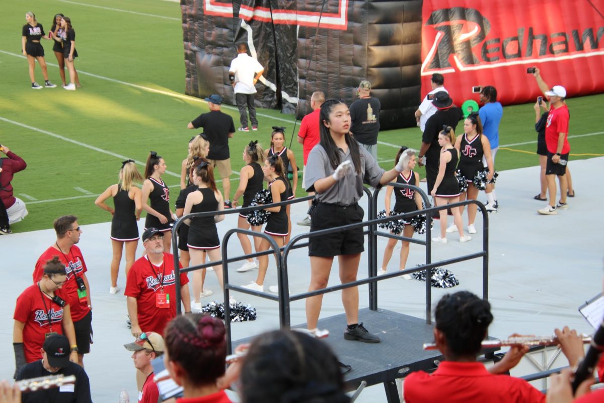 With the football team set to take the field at Toyota Stadium, drum major 
Hannah Lee gets the Redhawks band ready. 