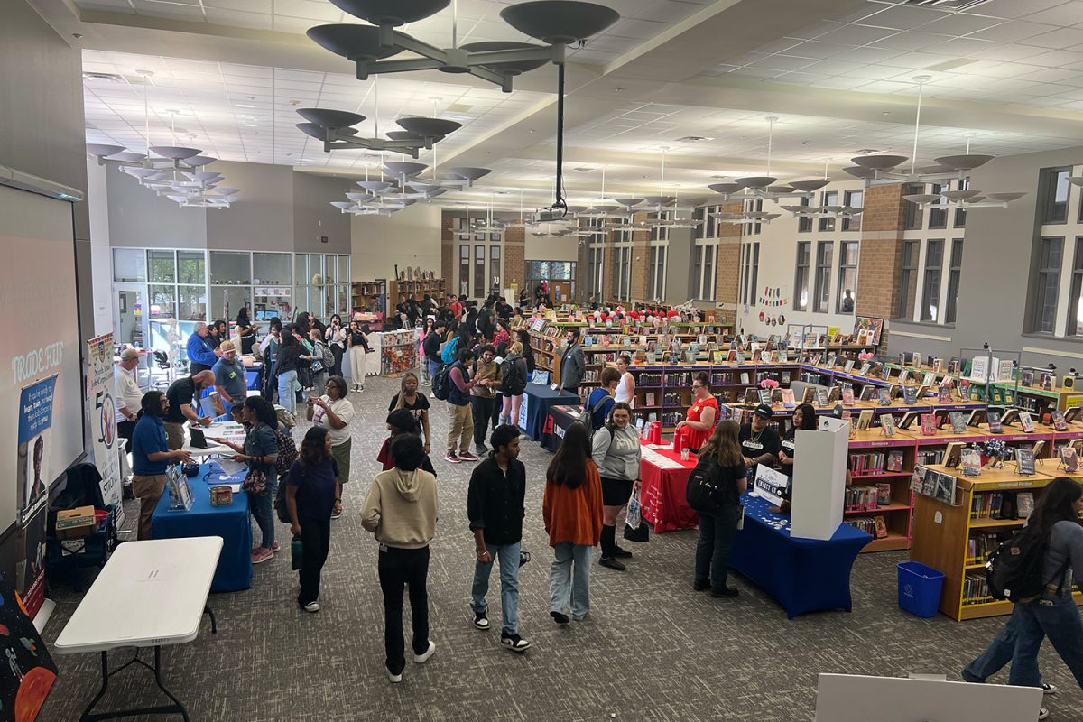Students mingle in the library for the 2nd Annual Trade Fair that brought more than a dozen businesses and schools to campus. 