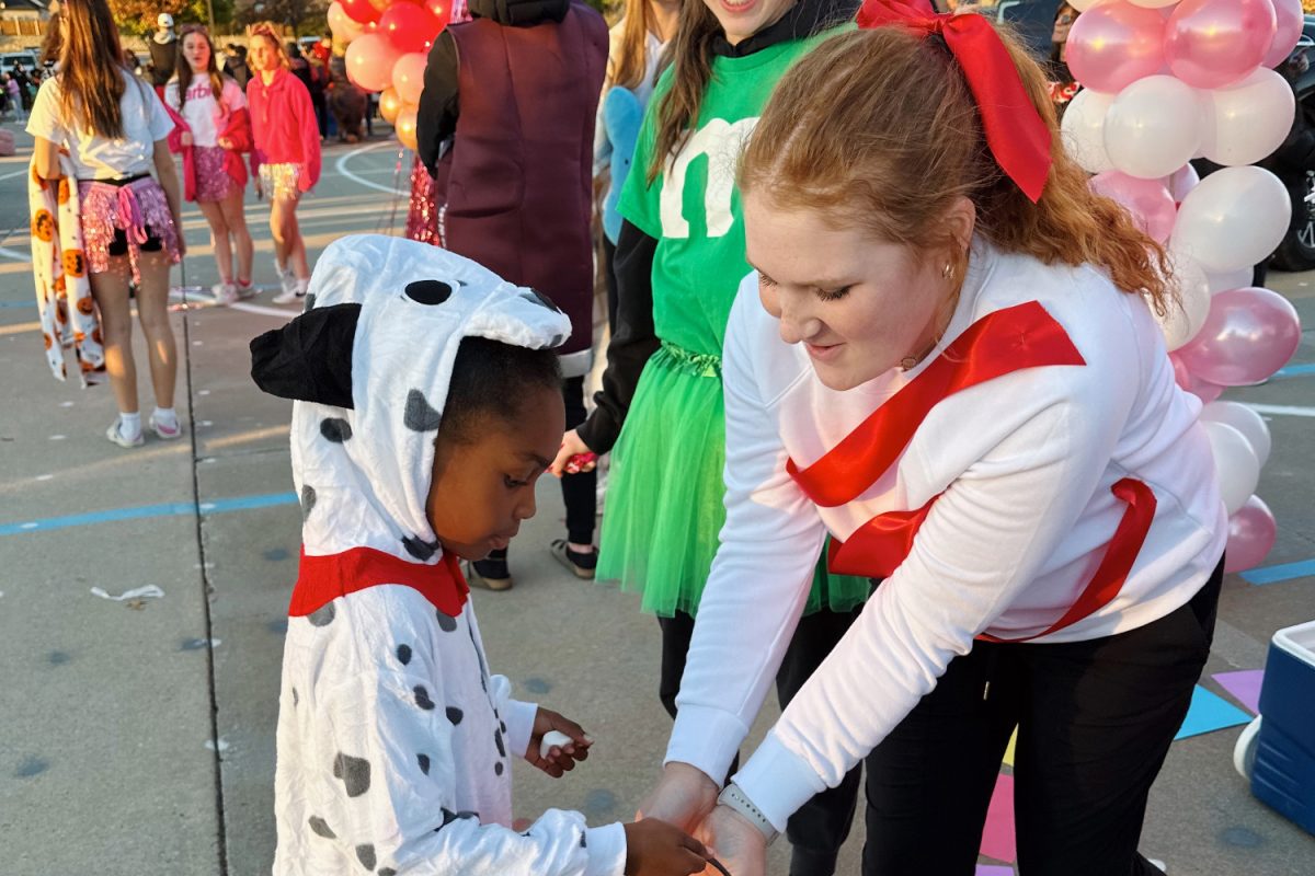 Junior, Ally Gerardot, hands candy to a little dalmation at the 2023 Trunk R Treat. 