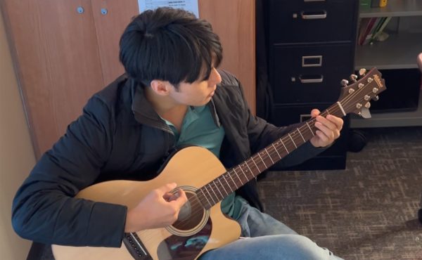 The soft sounds of an acoustic guitar can often be heard drifting out of the room of social studies teacher Scott Li who often practices and plays during class breaks. 