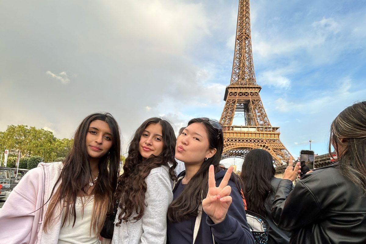 Standing in front of the Eiffel Tower are Christine Han, Rihanna Gopinathan, and Olivia Chamberlain. 