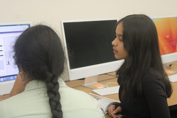 Sophomore Designer Harini Dammalapati (left) receives guidance from editor and senior Shivi Tripathi (right) as she works on her yearbook spread.