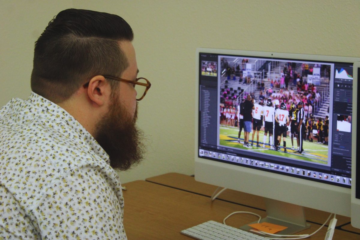 Yearbook adviser Andrew Lamas reviews previous shots from the Oct. 3 pink-out football game against Emerson, ensuring that key moments from the game are captured for the yearbook.