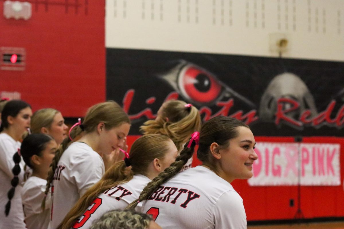 The hot pink stands out against senior Sophie Paulk's dark hair as she is all smiles looking onto the court, cheering on her teammates. 