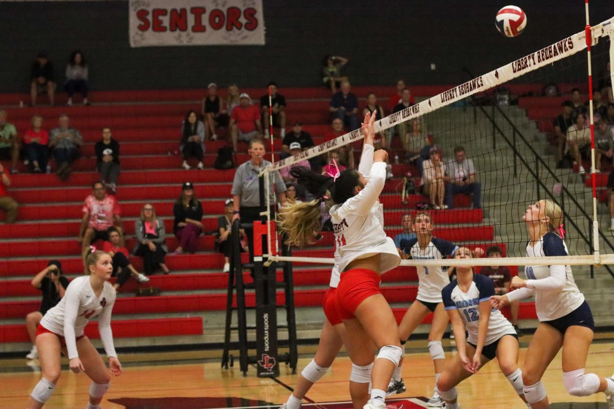 The hair on senior Sophia Hung's head, and the pink bow, symbolizing solidarity for breast cancer survivors and patients, swing full power as she tries to block the ball. 