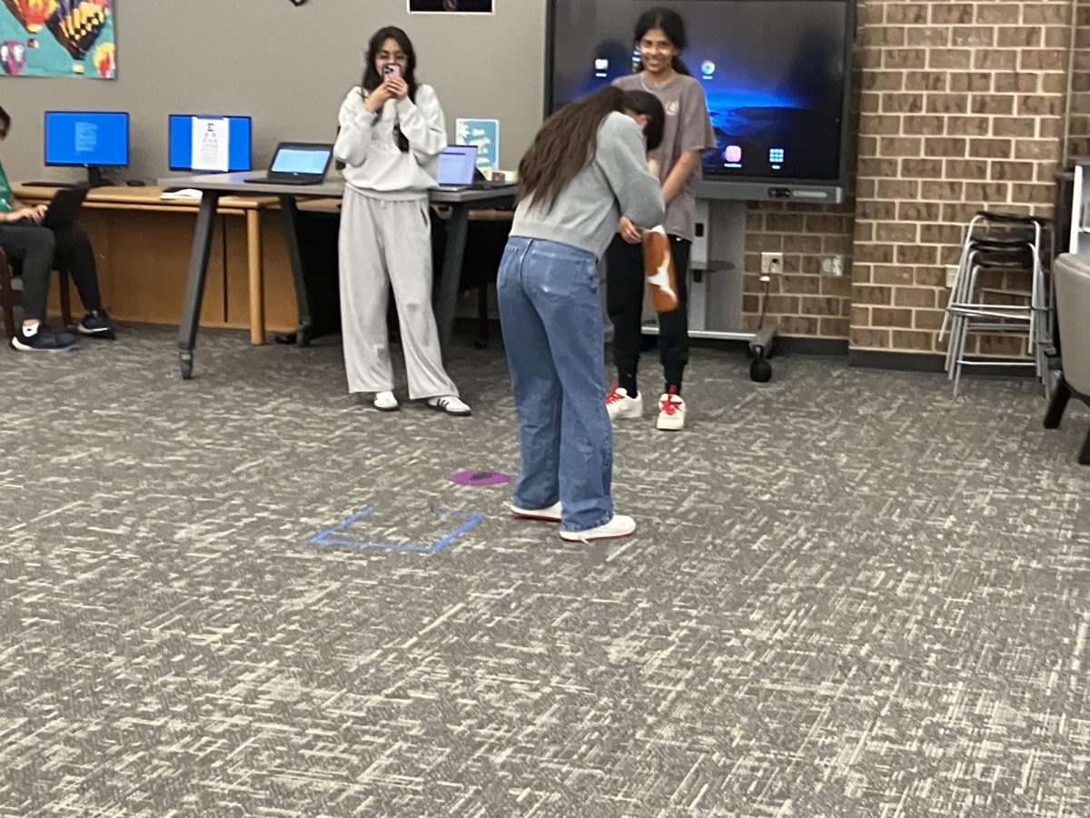 AP Psychology student, junior Hala Asadieh, spins around blinfolded to test her vestibular senses, as juniors Zaina Mirza and Reyna Gannamani watch.