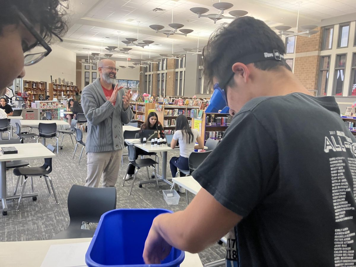 AP Psychology teacher Tim Johannes watches as junior Todd Stiles performs a variety of tasks while wearing goggles that give the sense of the world being upside down in order to test his perception.
