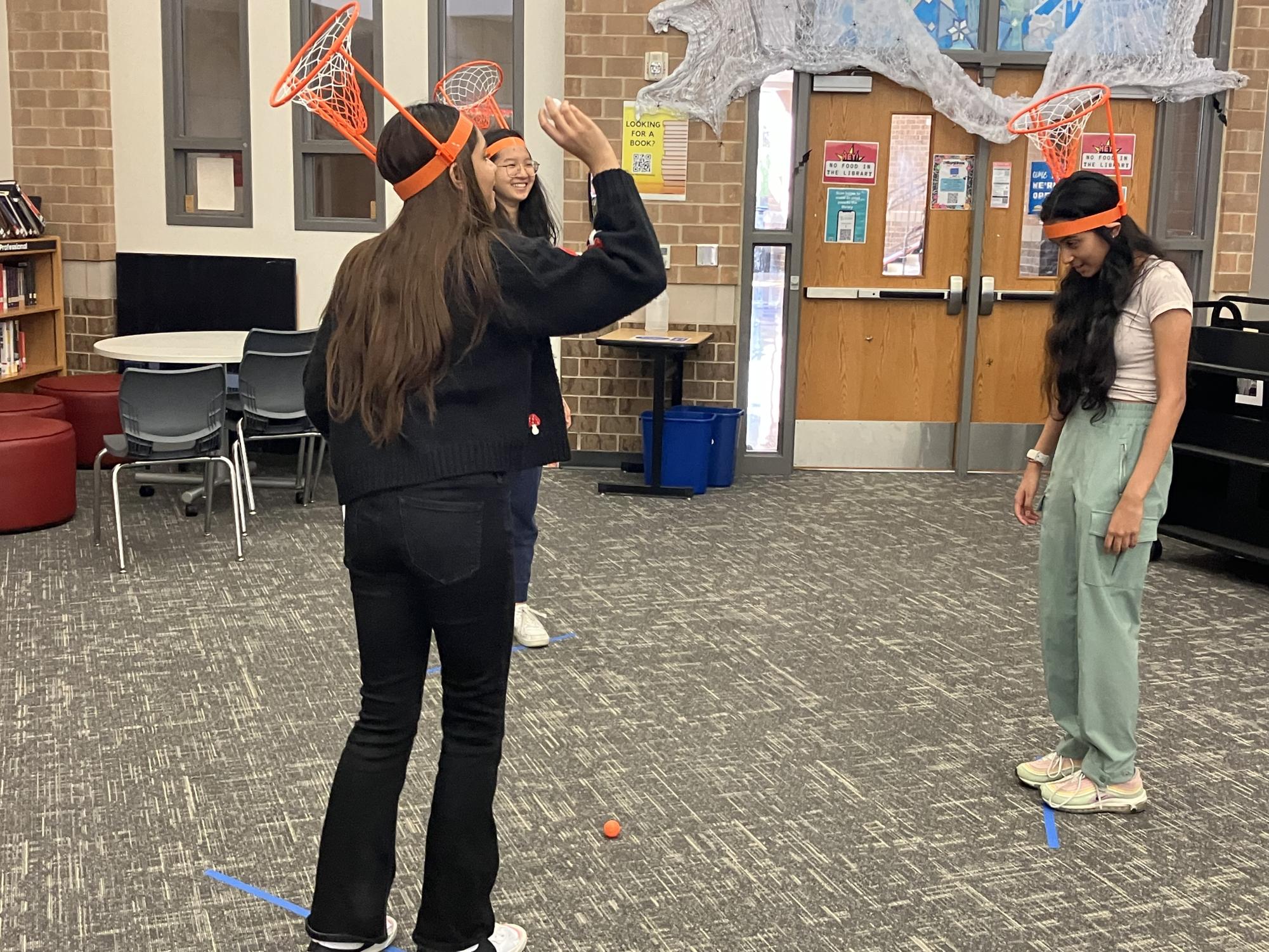 AP Psychology students, juniors Christina Huang, Hafsa Bajwa, and Zaina Mirza play basketball with head-mounted hoops to test senses and perception

