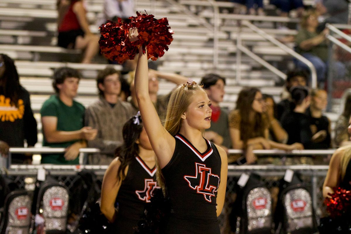 Senior Mackenzie Nelson cheers on the Redhawks at the football game against the Warriors. 