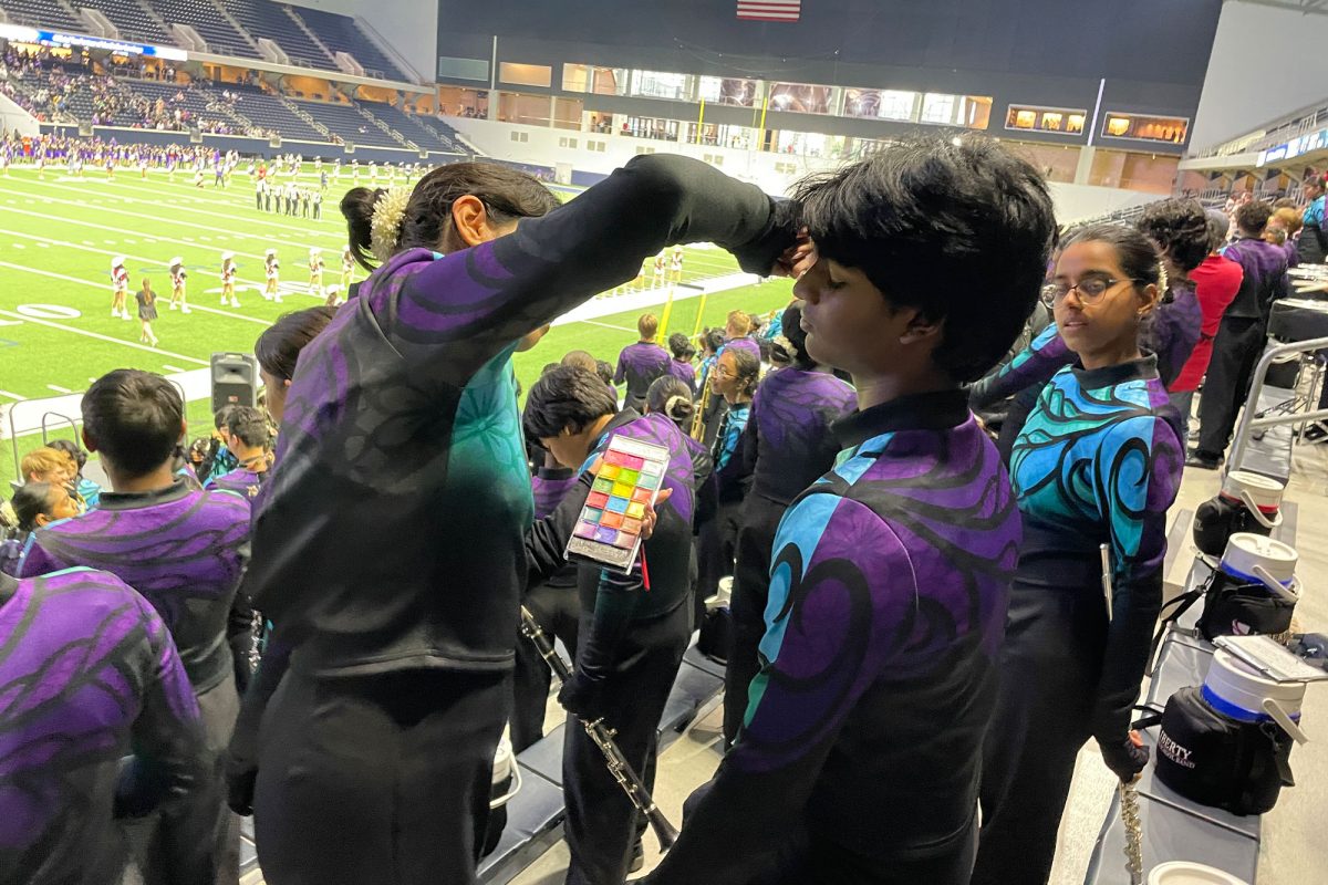 Though the band are in uniforms, they still find a way to stay on theme. Putting on their war paint, senior Regina Castro helps junior Natramizhnathan Seenuvasan with his face paint. 