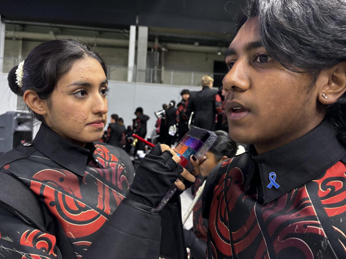 Caption: Senior Regina Castro Leal and junior Rahul Senthil Kumar Ketharidevi get into the Redhawk spirit with face paint and colon cancer pins.