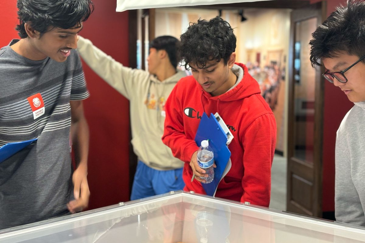 Seniors Mihir Poder, Rishub Rathod, and Kelvin Nguyen play a pinball game at the Federal Reserve Bank of Dallas.